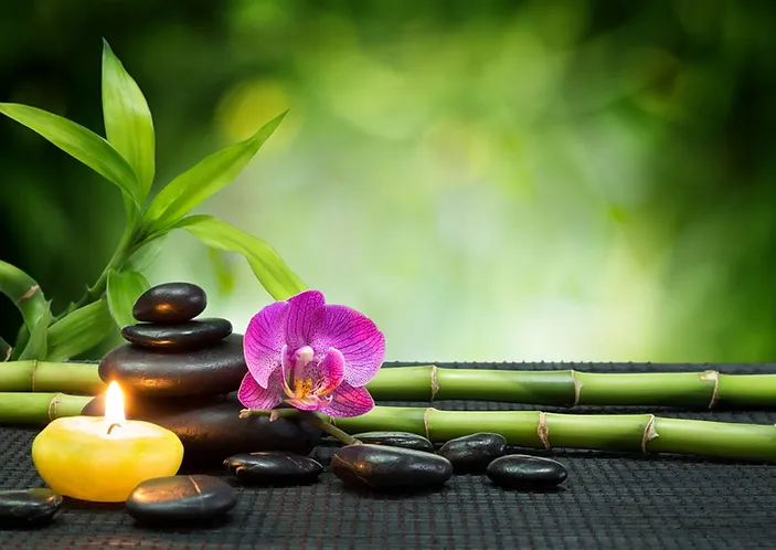 Image de détente sur fond vert, avec une bougie et des pierres de massage, ainsi qu'une fleur
